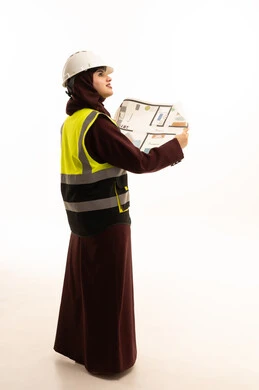 عمل النساء في القطاع الهندسي، مفهوم الهندسة والانشاءات المعمارية, بورترية من الخلف لمهندسة عربية خليجية سعودية محجبة ترتدي سترة الحماية والخوذة تمسك مخطط الإعمار, مراجعة وعرض مخطوطات المشاريع بشكل كامل, إدارة ومتابعة المشروع, الجسم بالطول الكامل، خلفية بيضاء