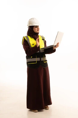 اجراء مكالمة عمل فيديوعبر جهاز الحاسوب المحمول، رفع كف الايد بتعابير السلام و التحية،  مهندسة عربية خليجية سعودية ترتدي ستره و خوذة الحماية تستخدم اللابتوب، الاشراف الالكتروني على تطبيق المشاريع و الخطط الهندسيه المعمارية في البناء، دمج العمل مع التقنية و التكنولوجيا ، الجسم بالطول الكامل، خلفية بيضاء