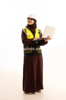 الاطلاع على تصاميم هندسية جديدة على جهاز الحاسوب المحمول، مهندسة عربية خليجية سعودية ترتدي ستره و خوذة الحماية تستخدم اللابتوب، الاشراف الالكتروني على تطبيق المشاريع و الخطط الهندسيه المعمارية في البناء، دمج العمل مع التقنية و التكنولوجيا، النظرالى شيء ما ، الجسم بالطول الكامل، خلفية بيضاء