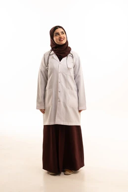 Standing upright and looking confidently at the camera, working in the healthcare sector, a portrait of an Arab Gulf Saudi female doctor wearing a medical coat looking at something, providing therapeutic services and medical examinations for patients, Saudi professions and jobs, gestures of happiness and joy, full-length body, white background.
