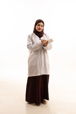 تقديم الاستشارات الطبية والخدمات الصحية، الاستماع إلى حالة المريض برحابة صدر و بشاشة، بورتريه لطبيبة عربية خليجية سعودية ترتدي المعطف الطبي تقوم بإعداد التقارير الطبية، مهن ووظائف سعودية، العمل في القطاع الصحي، الجسم بالطول الكامل، خلفية بيضاء