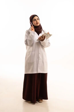 ايماءات محاولة تذكر شيء ما، تقديم الاستشارات الطبية والخدمات الصحية، الاستماع إلى حالة المريض برحابة صدر و بشاشة، بورتريه لطبيبة عربية خليجية سعودية ترتدي المعطف الطبي تقوم بإعداد التقارير الطبية، مهن ووظائف سعودية، العمل في القطاع الصحي، الجسم بالطول الكامل، خلفية بيضاء