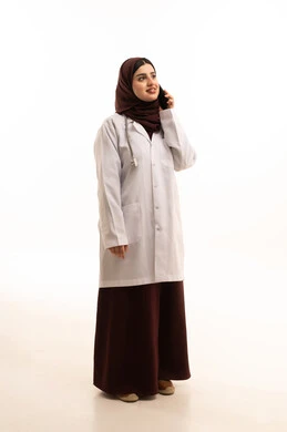 استخدام التقنيات الحديثه في مجال الطب، لتواصل مع المرضى عبر الهاتف المحمول, بورتريه لطبيبة عربية خليجية سعودية ترتدي المعطف الطبي تتحدث عبر الهاتف المحمول لتلبية مطالب الرعاية الصحية عن بعد، الجسم بالطول الكامل، خلفية بيضاء