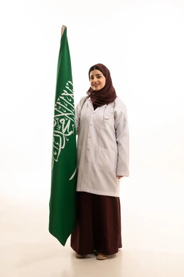 الاحتفال باليوم الوطني السعودي،  بورتريه لطبيبة عربية سعودية تلبس رداء وسماعة الطبيب تحمل  علم المملكة العربية السعودية،  النظر الى الكاميرا بايماءات الفخر و السعادة ، مهن ووظائف طبية، الجسم بالطول الكامل، خلفية بيضاء