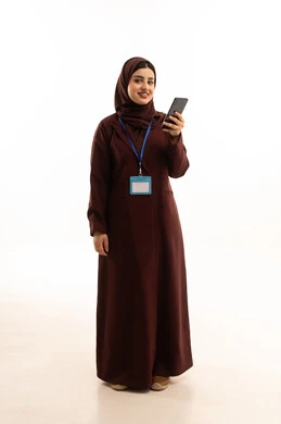 Chatting with family and friends, browsing social media applications and programs, gestures of joy and happiness, and a portrait of a Saudi Arabian Gulf woman wearing a hijab and an abaya, holding a mobile phone with an identification card with a blue ribbon, using modern and advanced technological devices, full-body, white background.