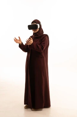 إيماءات التفاعل والاندماج مع الواقع الافتراضي، قضاء أوقات الفراغ بشكل ممتع، بورتريه لامرأة عربية خليجية سعودية ترتدي العباءة و الحجاب تضع نظارات الفي آر، استخدام الأجهزة التقنية الحديثة والتكنولوجيا في رؤية المشاهد الخيالية، الجسم بالطول الكامل، خلفية بيضاء