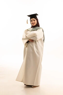 إيماءات السعادة بالوصول لحلم النجاح، بورتريه لخريجة عربية سعودية خليجية محجبة ترتدي ثوب التخرج الابيض والقبعة  تقف بأيدي متقاطعة تنظر إلى الكاميرا بتعابير النجاح، الاحتفال بإنهاء الدراسة الجامعية، حفلة التخرج من الجامعة, الجسم بالطول الكامل، خلفية بيضاء