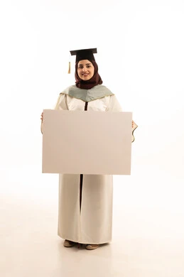 Celebration of completing university studies, a portrait of a Saudi Arabian Gulf female graduate wearing a white abaya and graduation cap, holding a white rectangular mock-up in her hand and looking at the camera with gestures of happiness and joy, explanatory boards and educational tools, full-body shot, white background.
