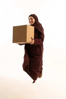 خدمات التوصيل السريع، عمليات الشحن الموثوقه, بورتريه لشابة عربية خليجية سعودية محجبة ترتدي عباءة تقفز في الهواء تحمل بيدها صندوق كرتوني ، العمل في توصيل الطلبات والبضائع للزبائن والعملاء, التسوق الالكتروني الآمن, استلام طلبات الاونلاين,الجسم بالطول الكامل، خلفية بيضاء
