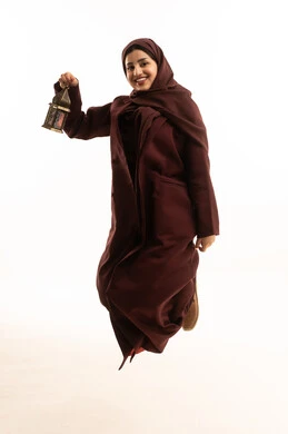 Religious occasions and holidays, an atmosphere of tranquility and spirituality, a portrait of a young Arab Gulf Saudi woman wearing a hijab and an abaya, jumping in the air, looking at the camera, holding a metal lantern in her hand, preparing for the arrival of the blessed month of Ramadan, worship and drawing closer to God, full-body shot, white background.