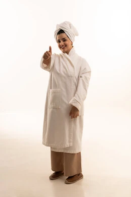 Looking at the camera with expressions of joy, a sign of quality and excellence, a feeling of admiration and satisfaction, a portrait of a Saudi Arabian Gulf woman wearing a white bathrobe and a towel, raising her thumb up in gestures of approval and agreement, full-body, white background. Looking at the camera with expressions of joy, a sign of quality and excellence, a feeling of admiration and satisfaction, a portrait of a Saudi Arabian Gulf woman wearing a white bathrobe and a towel, raising her thumb up in gestures of approval and agreement, full-body, white background.