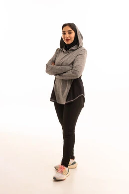 ايماءات السرور والسعادة، نمط حياة صحي ومفيد،مفهوم الرشاقة واللياقة، انشطة بدنية نسائية، تقوية العضلات ونحت الجسم، بورتريه لشابة عربية خليجية سعودية ترتدي زي رياضي تنظر الى الكاميرا بايدي متقاطعة ، خلفية بيضاء