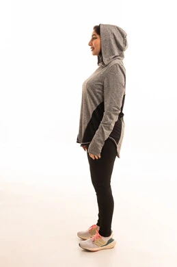A healthy and beneficial lifestyle, gestures of joy and happiness, the concept of agility and fitness, women's physical activities, muscle strengthening and body sculpting, a side portrait of a young Arab Gulf Saudi woman wearing sportswear looking at the camera with crossed arms, white background.