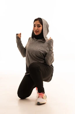 ممارسة التمارين الرياضية مع الدمبل، بورتريه لفتاة عربية خليجية سعودية ترتدي الملابس الرياضية،نشاط بدني للمحافظة على الصحة واللياقة الجسدية، أسلوب حياة صحي،  تمارين رفع الأثقال (دمبلز)، رفع الأوزان الحديدية الثقيلة، صورة بالطول الكامل، خلفية بيضاء