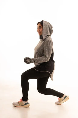 رفع الأوزان الحديدية الثقيلة، بورتريه لفتاة عربية خليجية سعودية ترتدي الملابس الرياضية، ممارسة التمارين الرياضية مع الدمبل، نشاط بدني للمحافظة على الصحة واللياقة الجسدية، أسلوب حياة صحي،  تمارين رفع الأثقال (دمبلز)،  صورة بالطول الكامل، خلفية بيضاء