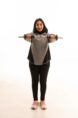 بورتريه لفتاة عربية خليجية سعودية ترتدي الملابس الرياضية، ممارسة التمارين الرياضية مع الدمبل، نشاط بدني للمحافظة على الصحة واللياقة الجسدية، كمال الأجسام، أسلوب حياة صحي، بناء عضل، تمارين رفع الأثقال (دمبلز)، رفع الأوزان الحديدية الثقيلة، صورة بالطول الكامل، خلفية بيضاء