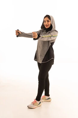 A portrait of a young Arab Gulf Saudi woman wearing sportswear, practicing resistance exercises to tone and strengthen muscles, engaging in physical activities using resistance bands, a physical activity to enhance fitness and physical health, the concept of agility and physical activity, a healthy and beneficial lifestyle, with a white background.