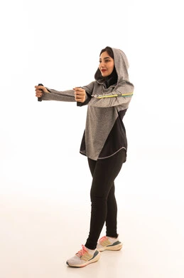 مفهوم الرشاقة والنشاط البدني، ممارسة التمارين الرياضية باستخدام الحبال المطاطية، نشاط بدني لتعزيز اللياقة والصحة الجسدية، بورتريه لشابة عربية خليجية سعودية ترتدي زيًا رياضيًا تمارس تمارين المقاومة لشد وتقوية العضلات، أسلوب حياة صحي ومفيد، خلفية بيضاء.