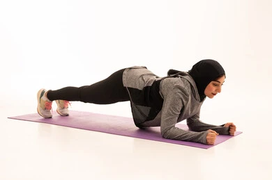 نمط حياة صحي ومفيد،المحافظة على التوازن الجسدي، ممارسة التمرينات الأرضية لشد الجسد، مفهوم الرشاقة واللياقة، انشطة بدنية نسائية، تقوية العضلات ونحت الجسم، بورتريه لشابة عربية خليجية سعودية ترتدي زي رياضي تقوم بممارسة التمرينات الرياضية ،إيماءات الحماس و النشاط، خلفية بيضاء