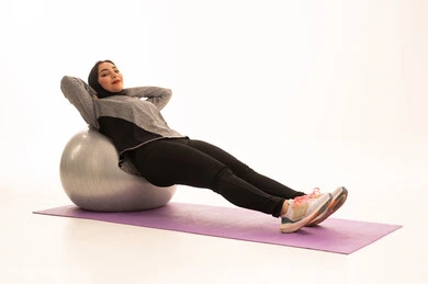 Exercising with a fitness ball, an Arab Gulf Saudi girl wearing sportswear, physical activity to maintain health and physical fitness, a healthy lifestyle, practicing Pilates ball and balance exercises, white background. Exercising with a fitness ball, an Arab Gulf Saudi girl wearing sportswear, physical activity to maintain health and physical fitness, a healthy lifestyle, practicing Pilates ball and balance exercises, white background.