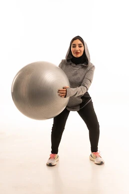 انشطه رياضيه ممتعه ، فتاة عربية خليجية سعودية ترتدي الملابس الرياضية، ممارسة التمارين الرياضية مع كرة اللياقة البدنية، نشاط بدني للمحافظة على الصحة واللياقة الجسدية، أسلوب حياة صحي، ممارسة تمارين كرة بيلاتيس والتوزان، خلفية بيضاء