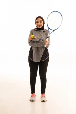 Training to master the game, a portrait of a Saudi Arabian Gulf woman wearing a hijab dressed in special attire for the game and playing tennis, a fun and beneficial sport, a game characterized by focus and quick wit, practicing a favorite hobby, entertainment and recreation, health and fitness.