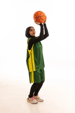 إيماءات التشجيع و الحماس، الشغف بالألعاب الرياضية , ممارسة هواية كرة السلة , بورتريه لامرأة عربية خليجية سعودية ترتدي ملابس رياضية تمسك الكرة , الفريق السعودي النسائي , صورة للجسم بالكامل ،خلفية بيضاء