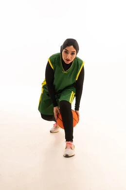 الفريق السعودي النسائي ,الشغف بالألعاب الرياضية , ممارسة هواية كرة السلة , بورتريه لامرأة عربية خليجية سعودية ترتدي ملابس رياضية تمسك الكرة بإيماءات التشجيع و الحماس , صورة للجسم بالكامل ،خلفية بيضاء