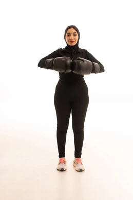 المحافظة على اللياقة البدنية، زيادة قدرة العضلات على التحمل، بورتريه لفتاة عربية خليجية سعودية ترتدي الملابس الرياضية والقفازات تنظر إلى الكاميرا تتعلم فنون الملاكمة، التدرب على الحركات القتالية ، تعزيز صحة العظام والمفاصل، خلفية بيضاء