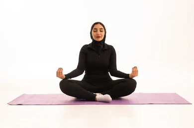 Practicing yoga, a healthy and beneficial lifestyle, the concept of agility and fitness, women's physical activities, strengthening muscles and sculpting the body, a portrait of a young Arab Gulf Saudi woman wearing sportswear exercising, white background.