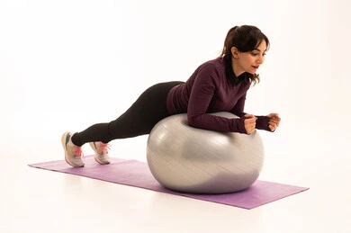 Physical activity to maintain health and physical fitness, practicing exercises with a fitness ball, an Arab Gulf Saudi girl wearing sportswear, a healthy lifestyle, practicing Pilates ball and balance exercises, white background.
