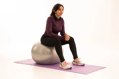 Exercising with a fitness ball, an Arab Gulf Saudi girl wearing sportswear, physical activity to maintain health and physical fitness, a healthy lifestyle, practicing Pilates ball and balance exercises, white background.