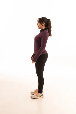 تقوية العضلات ونحت الجسم،نمط حياة صحي ومفيد، مفهوم الرشاقة واللياقة،ايماءات السرور والسعادة،انشطة بدنية نسائية، بورتريه من الجانب لشابة عربية خليجية سعودية ترتدي زي رياضي تقف باستقامه ، خلفية بيضاء