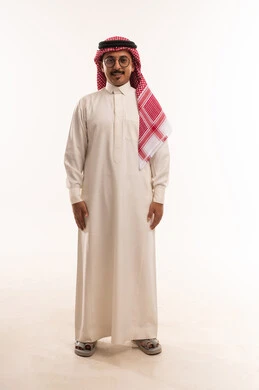 الوقوف باستقامة والنظر إلى الكاميرا بايماءات سعادة و سرور, ، الاهتمام بالمظهر الخارجي والأناقة، بورتريه  لرجل عربي خليجي سعودي يرتدي الثوب والشماغ التقليدي ويضع نظارات طبية، مفهوم الرجولة والخشونة، صورة الجسم بالطول الكامل، خلفية بيضاء