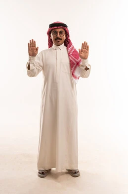 A stop or surrender signal, raising hands up and lifting palms, the concept of masculinity and toughness, concern for external appearance and elegance, a portrait of an Arab Gulf Saudi man wearing traditional attire and a shemagh, a young Saudi man wearing glasses, full-body image, white background.