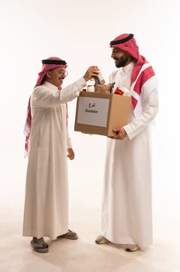 Spending and donating for the sake of God to Saudi associations, a portrait of two Gulf Arab Saudi men preparing a food box, donating to the food basket project, providing food for the needy, humanitarian charitable initiatives and donations, Islamic associations in Saudi Arabia, the month of Ramadan, white background.