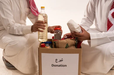 Providing a food basket and children's clothing, the concept of assistance and donation, food items for donation and bringing joy to the hearts of children, participating in rewards, Islamic charities in Saudi Arabia, helping to provide basic needs, a portrait of two Arab Gulf men from Saudi Arabia, white background.