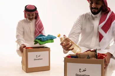 مفهوم المساعدة والتبرع، توفير سلة غذائية وملابس أطفال، مواد غذائي للتبرع وادخال البهجة على قلب الصغار،المشاركة في الثواب،  جمعيات اسلامية في السعودية، المساعدة على توفير الاحتياجات الاساسية، بورتريه لرجلان خليجيان عربيان سعوديان ، خلفية بيضاء