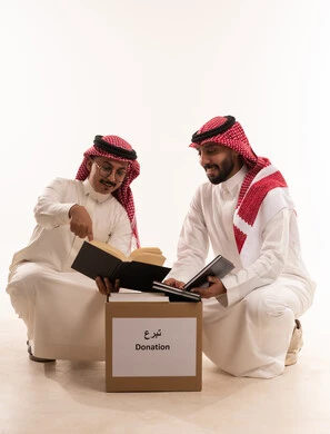 جمعيات اسلامية في السعودية، التبرع لمشروع الكتب والمستلزمات المدرسية،المساعدة على التعلم من خلا مبادرات وتبرعات انسانية خيرية،  بورتريه لرجلان خليجيان عربيان سعوديان يقومان بتجهيز صندوق التبرع، توزيع الحصص المجهزة، خلفية بيضاء
