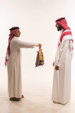 التبرع لمشروع اطعام الجائع، كيس أرز للتبرع في شهر رمضان،جمعيات اسلامية في السعودية، المساعدة على اطعام الصائمين المساكين في أيام فضيلة،  بورتريه لرجلان خليجيان عربيان سعوديان يقومان بتجهيز صندوق التبرع، توزيع الحصص المجهزة، خلفية بيضاء