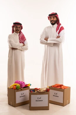 توفير وسائل التسلية والترفيه، ألعاب أطفال للتبرع وادخال البهجة على قلب الصغار،المشاركة في الثواب،  جمعيات اسلامية في السعودية، المساعدة على توفير الاحتياجات، بورتريه لرجلان خليجيان عربيان سعوديان يقومان بتجهيز صندوق التبرع، توزيع الحصص المجهزة، خلفية بيضاء