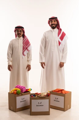 النظر إلى الكاميرا بايماءات السرور والسعادة، ألعاب أطفال للتبرع وادخال البهجة على قلةب الصغار، جمعيات اسلامية في السعودية، المساعدة على توفير الاحتياجات، بورتريه لرجلان خليجيان عربيان سعوديان يقومان بتجهيز صندوق التبرع، توزيع الحصص المجهزة، خلفية بيضاء