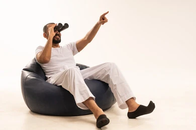 التخطيط المستقبلي للأهداف والطموحات, مفهوم التسليه والترفيه، قضاء أوقات ممتعة في عطلة نهاية الاسبوع، أنشطة وفعاليات مسلية،  بورتريه لرجل عربي سعودي خليجي يرتدي سروال وفانيلا أبيض يجلس على كرسي مريح ويضع على عيونه منظار، خلفية بيضاء