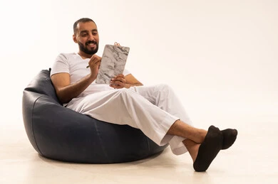 تعابير التفكير لاتخاذ القرارات, تدوين و تسجيل الملاحظات, التخطيط المستقبلي للأهداف والطموحات, بورتريه  لرجل عربي سعودي خليجي يرتدي سروال وفانيلا أبيض يجلس على كرسي مريح ويمسك بيديه مفكرة وقلم يقوم بكتابة المعلومات, ، خلفية بيضاء