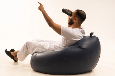 الاشارة بإصبع السبابة الى شيء ما، حب الاستكشاف والمغامرة، رؤية الاشياء البعيدة و تقريبها, التخطيط المستقبلي للأهداف والطموحات,  أنشطة وفعاليات مسلية، بورتريه من الخلف لرجل عربي سعودي خليجي يرتدي سروال وفانيلا أبيض يجلس على كرسي مريح ويضع على عيونه منظار، خلفية بيضاء