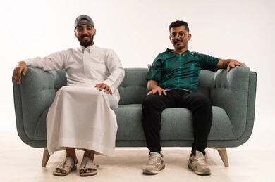 الشغف في متابعة فريق المنتخب الوطني، المناقشة والحوار حول المباريات، قضاء اوقات الفراغ الممتعة مع الاصدقاء، الحماس والتفاعل مع المنتخب، بورتريه لرجلين عربيين خليجيين سعوديين احدهما يرتدي الثوب التقليدي، شاب سعودي يرتدي قميص المنتخب السعوديي، خلفية بيضاء