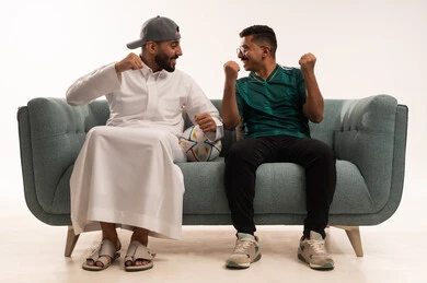 ايماءات التحدي والانتصار، قضاء اوقات الفراغ الممتعة مع الاصدقاء، الحماس والتفاعل مع المنتخب، أنشطة رياضية ترفيهية، الشغف في متابعة فريق المنتخب الوطني، بورتريه لرجلين عربيين خليجيين سعوديين احدهما يمسك بيده كرة، شاب سعودي يرتدي قميص المنتخب السعوديي، خلفية بيضاء