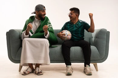 الحماس والتفاعل مع المنتخب، أنشطة رياضية ترفيهية، قضاء اوقات الفراغ الممتعة، الشغف في متابعة فريق المنتخب الوطني، بورتريه لرجلين عربيين خليجيين سعوديين احدهما يضع على أكتافه علم المملكة، شاب سعودي يرتدي قميص المنتخب السعوديي ويحمل كرة،خلفية بيضاء