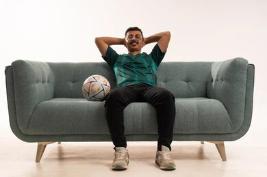 تعابير الفخر والثقة بالفريق وضع اليدين خلف الرأس، التفاعل بمشاهدة الفريق المفضل, ايماءات التحدي والانتصار، الألعاب والمباريات الرياضية, أنشطة رياضية ترفيهية،  بورتريه لشاب سعودي يرتدي قميص المنتخب السعوديي وبجانبه كرة، خلفية بيضاء