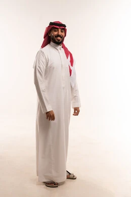 الرجولة والاناقة والاهتمام بالمظهر الخارجي، الوقوف باستقامة والنظر إلى الكاميرا بتعابير السرور، بورتريه لرجل عربي خليجي سعودي يرتدي الثوب والشماغ التقليدي، الطول الكامل للجسم، خلفية بيضاء
